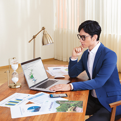 man thinking deep at workdesk with laptop and paper with different charts