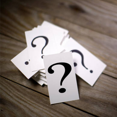a stack of white cards with a black question mark, on the wooden table