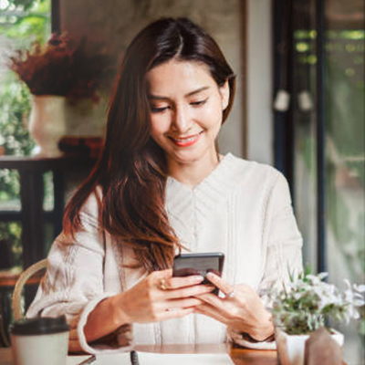 lady with long hair using mobile with a smile in cafe