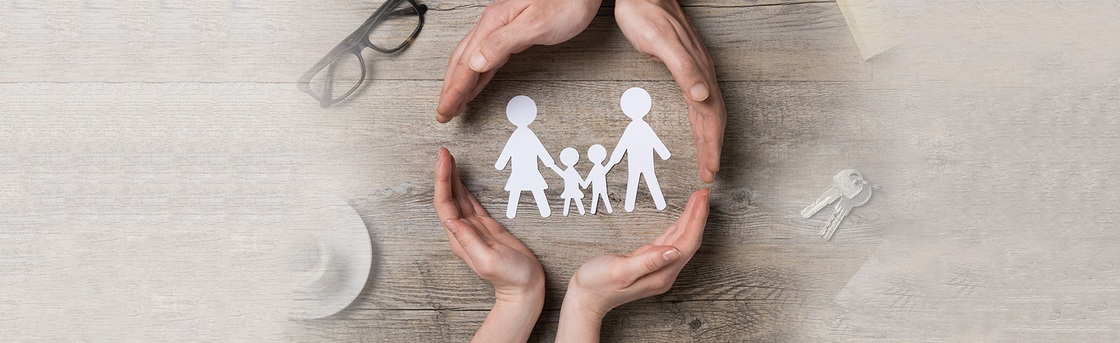 hands surrounding a family-shaped paper cut silhouette