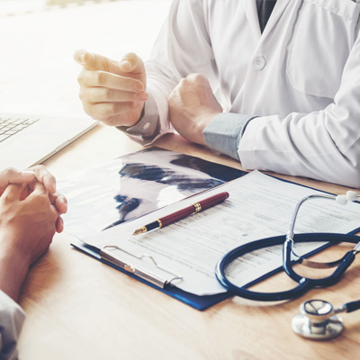 discussion of patient and doctor with Xray film, report and laptop on the desk